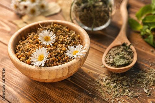 Bowl with dried chamomile flowers on wooden table