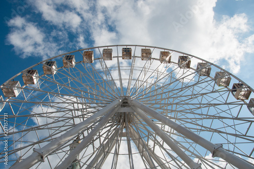 Ferris wheel in an amusement park  view from below. Sky background with clouds with place for text.