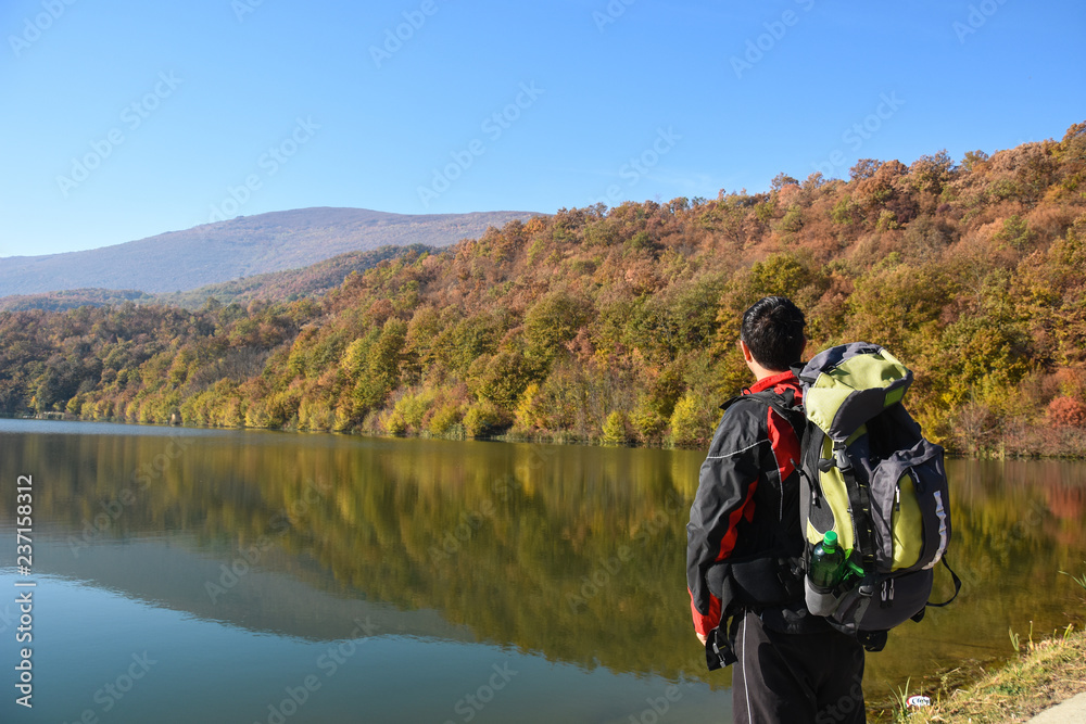 an with backpack next to a lake in autumn. Man in nature, concept of healthy life and traveling
