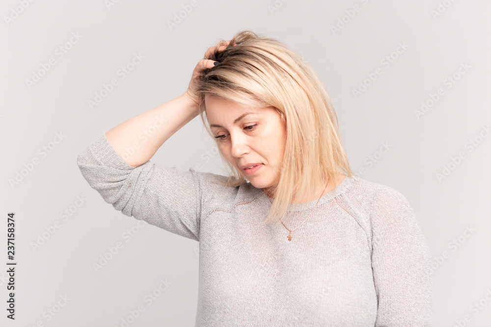 Portrait of middle aged adult woman feeling head ache, pain or high blood pressure facial expression on grey background Portrait of middle aged adult woman feeling head ache, pain or high blood pressure facial expression on grey background