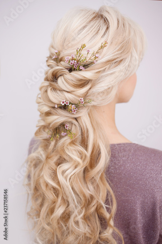 Back view of an elegant trendy hairstyle, interlacing curls and decorating with flower petals