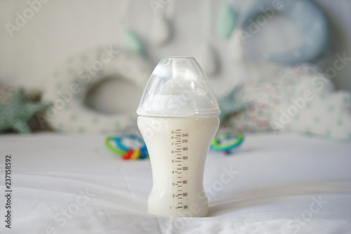 Feeding bottle of baby formula on bed
