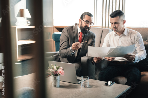 Obraz na plátne Young businessman talking to his bearded investor wearing glasses