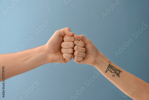 Man and woman bumping fists on color background photo