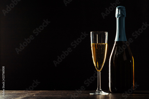 bottle of champagne and glasses over dark background