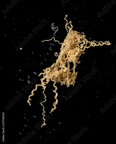 Instant noodles with soup splash or explosion flying in the air over dark background