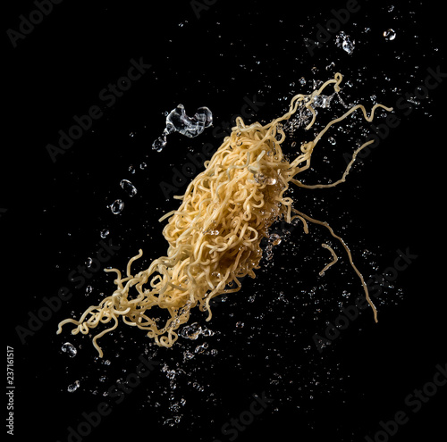 Instant noodles with soup splash or explosion flying in the air over dark background photo