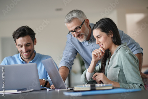  Young colleagues with older boss working with computers photo