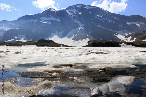 Calm sunny day on italian Alps, Col del Nivolet, lake. snow, ice, mountain