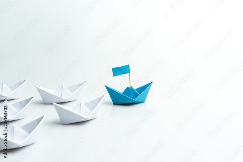 Leadership concept, blue paper ship leading among white on white background. - obrazy, fototapety, plakaty 