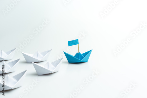 Papier peint Leadership concept, blue paper ship leading among white on white background