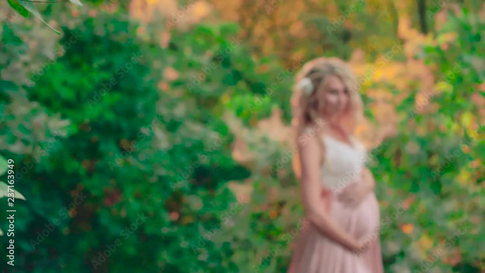 a smooth transition of nature shooting to a pregnant woman with blond light hair, which stands in a long elegant pink dress with a lace top, touching photo session during the happy pores of pregnancy a smooth transition of nature shooting to a pregnant woman with blond light hair, which stands in a long elegant pink dress with a lace top, touching photo session during the happy pores of pregnancy