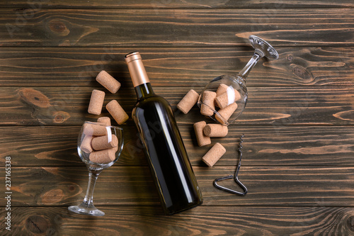 Bottle of wine with corks and glasses on wooden background