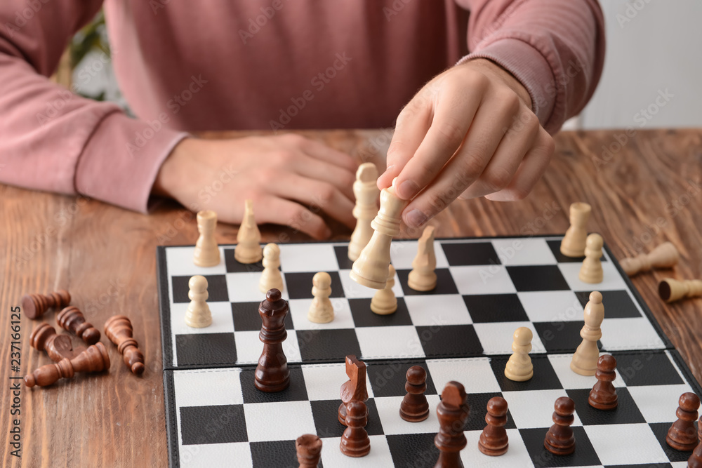 Man playing chess on wooden table Man playing chess on wooden table