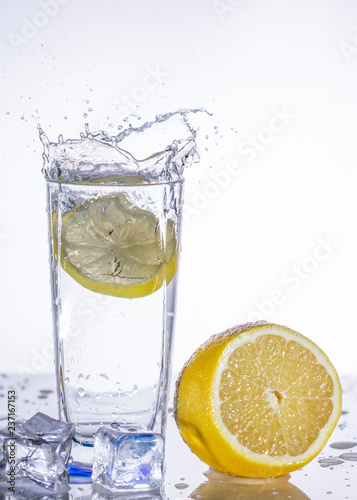 A glass of lemonade on a light background with splashing water