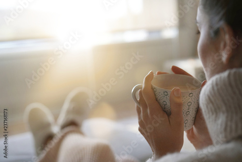 Cosy brunette at home on couch with hot drink photo