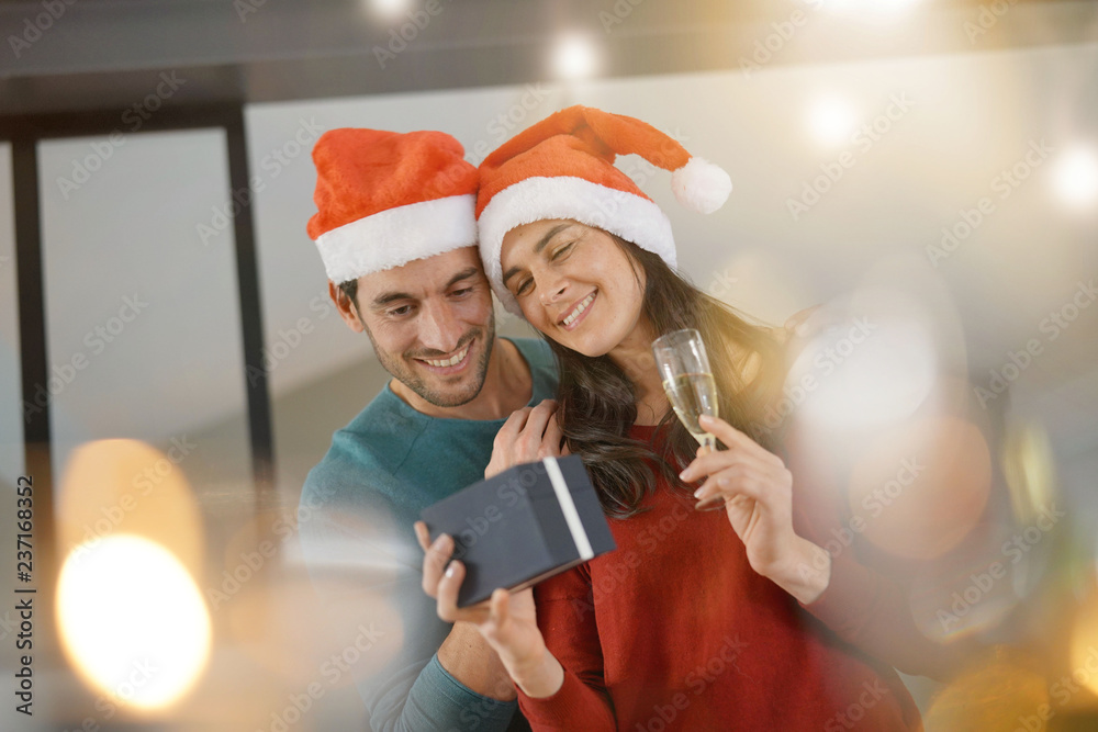 Gorgeous couple celebrating Christmas at home with champagne and gifts Gorgeous couple celebrating Christmas at home with champagne and gifts
