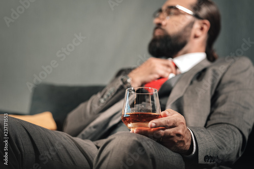 Bearded businessman having nervous breakdown drinking cognac