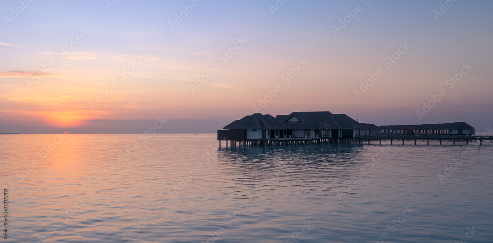 Incredible orange sunset over the turquoise lagoon, with water bungalows in Maldives