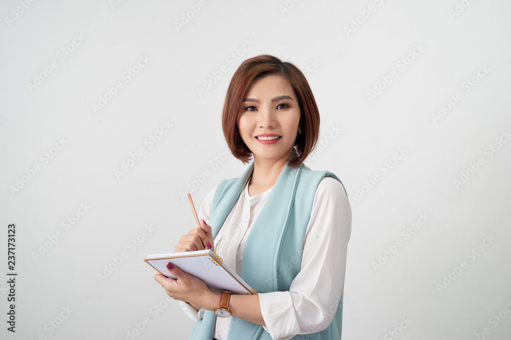 Portrait of young smiling businesswoman in the office, holding documents on light background Portrait of young smiling businesswoman in the office, holding documents on light background