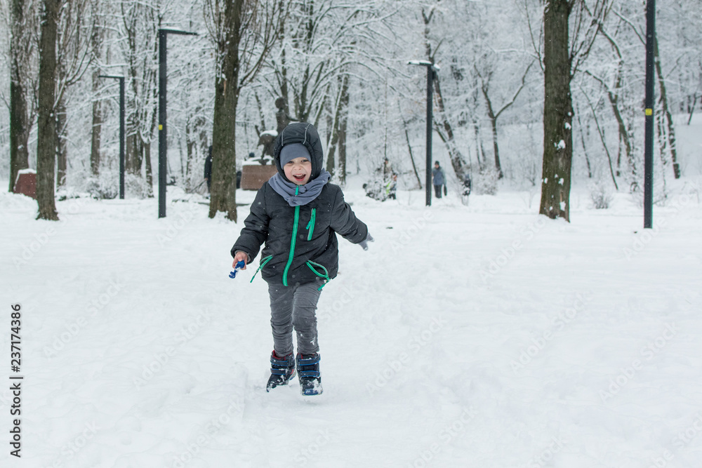 A little boy runs through the snow in the park. A little boy runs through the snow in the park.