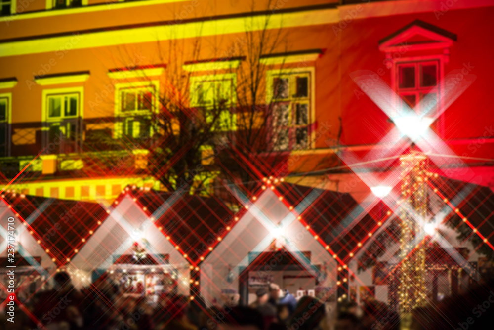 Crowded Christmas market in city center, decorated wooden huts with glowing lights. People enjoying event and searching for gifts. Beautiful Christmas background. 