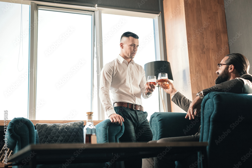 Two business partners drinking alcohol after long working day Two business partners drinking alcohol after long working day