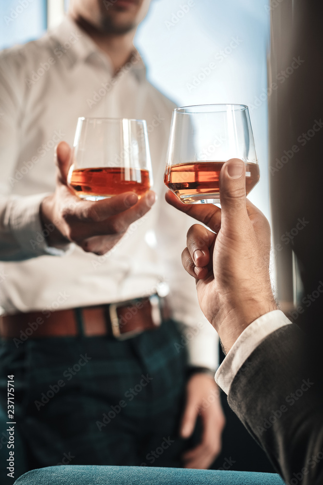 Man wearing squared trousers drinking whisky with business partner