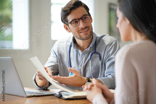  Modern young doctor speaking to patient in office
