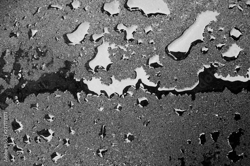 Dark drops of liquid on a hard surface. Fresh asphalt and fuel drops. Wet surface texture.