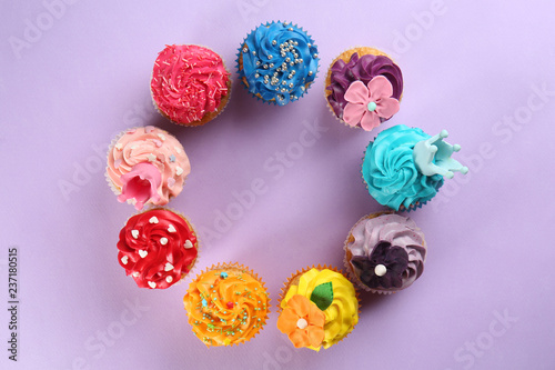 Frame made of delicious cupcakes on color background