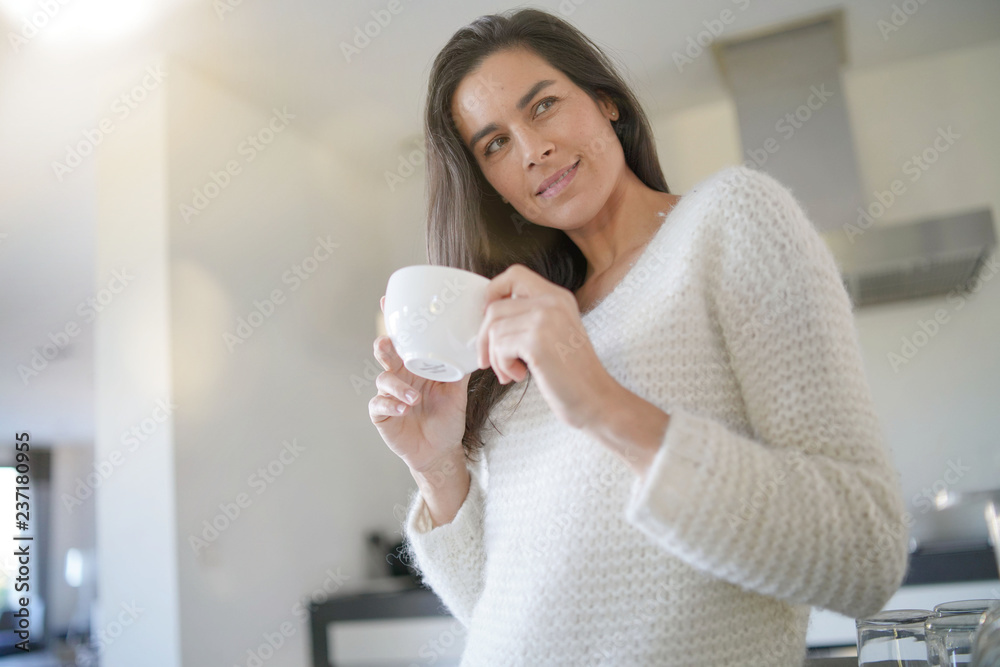 Stunning brunette woman with cup of coffee in modern kitchen Stunning brunette woman with cup of coffee in modern kitchen