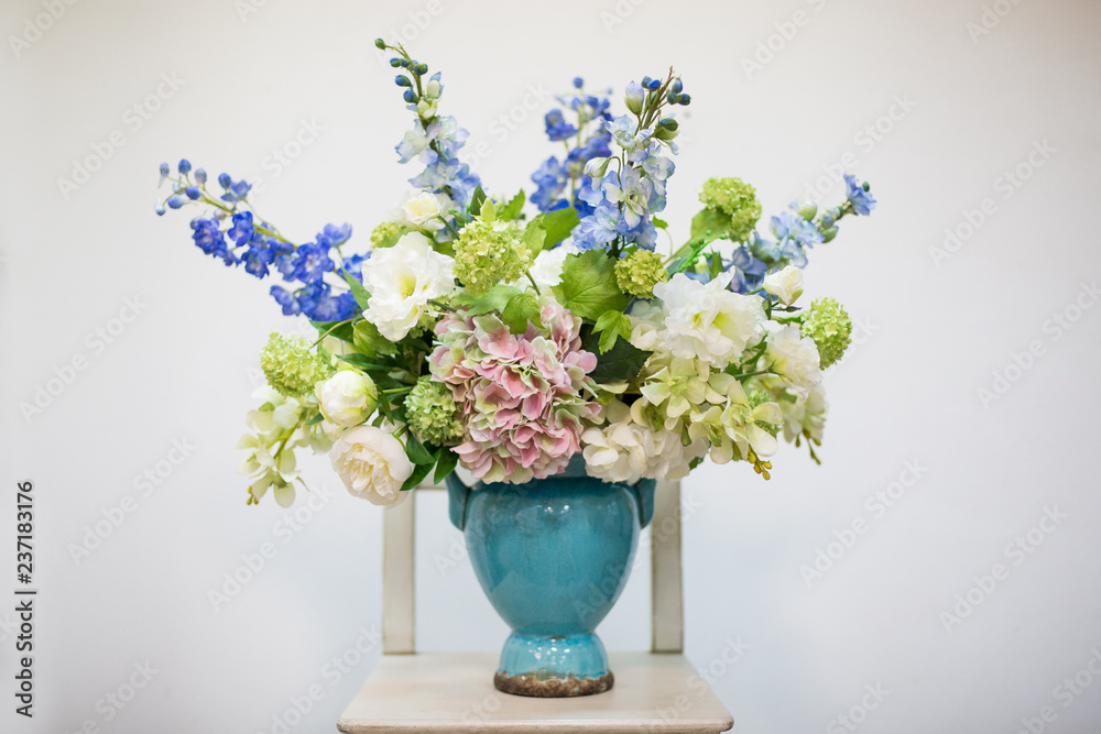 Delicate volumetric bouquet of flowers in a blue vase on a light background