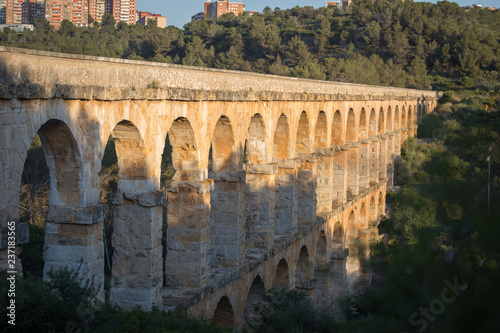 Ancient viaduct bridge from the bottom view in the setting sun photo