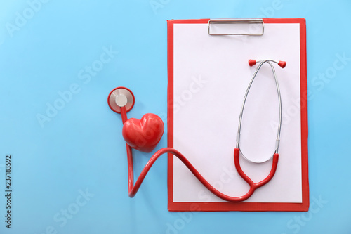 Obraz na plátne Medical stethoscope with red heart and clipboard on color background