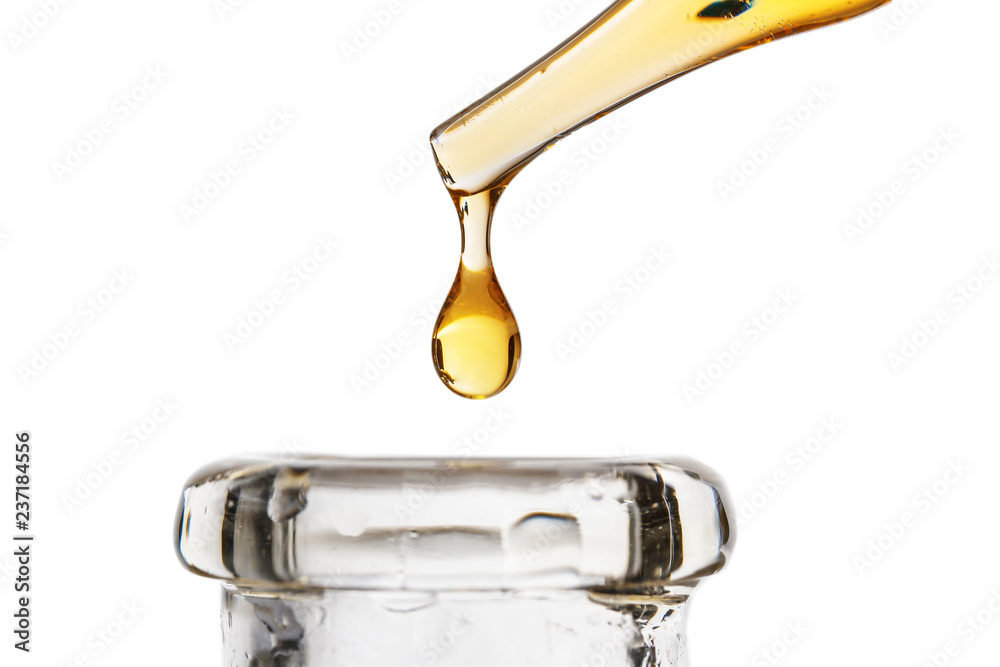 Dripping oil from pipette into glass bottle on white background - obrazy, fototapety, plakaty 