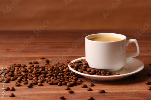 Cup of aromatic coffee and coffee beans on a wooden background.