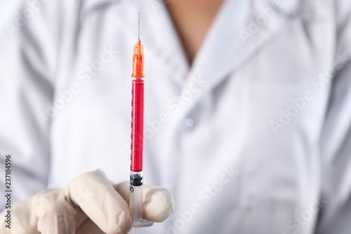 Doctor holding syringe full of liquid, closeup photo
