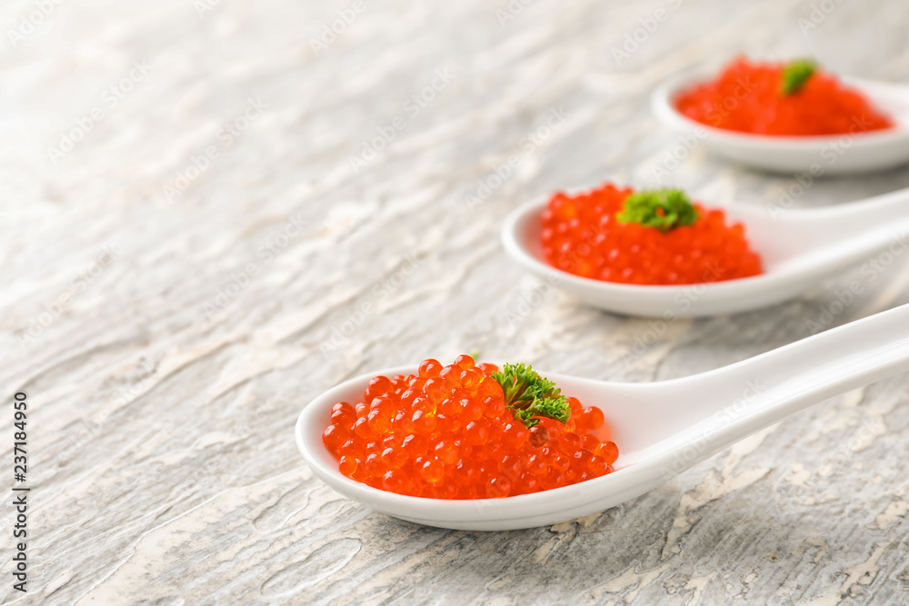 Spoons with delicious red caviar on light table Spoons with delicious red caviar on light table