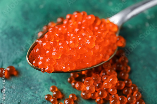 Spoon with delicious red caviar on color table