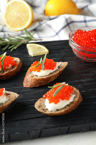 Delicious sandwiches with red caviar on wooden board