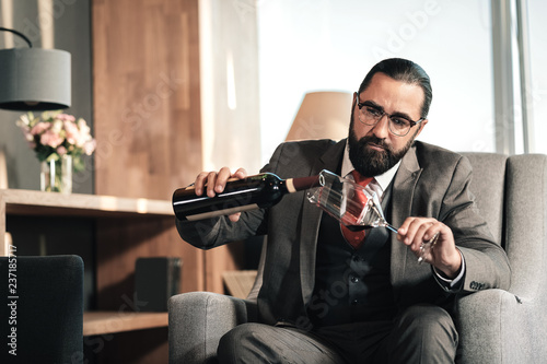 Tired businessman pouring some wine into his glass