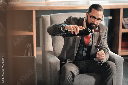 Man wearing nice expensive hand watch pouring wine into glass