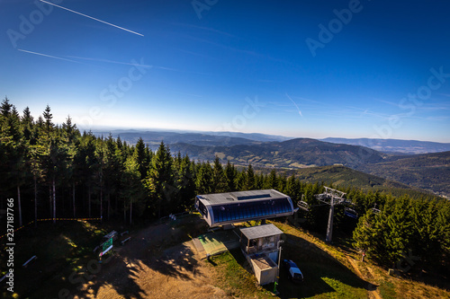 Summer view on top station of Kouty nad Desnou slope with green coniferous trees and dark blue sky