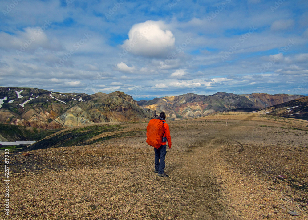 Experienced male hiker hiking alone into the wild admiring volcanic landscape with heavy backpack. Travel lifestyle adventure wanderlust concept