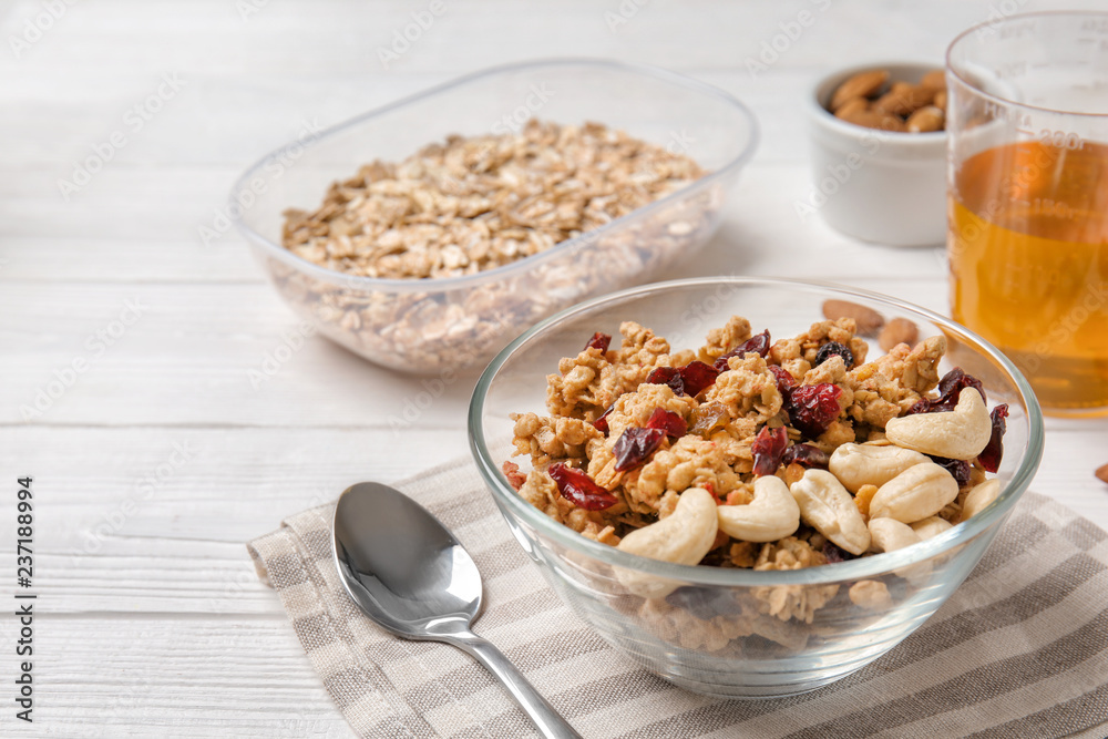 Granola with dried fruits and nuts in bowl on white wooden table Granola with dried fruits and nuts in bowl on white wooden table