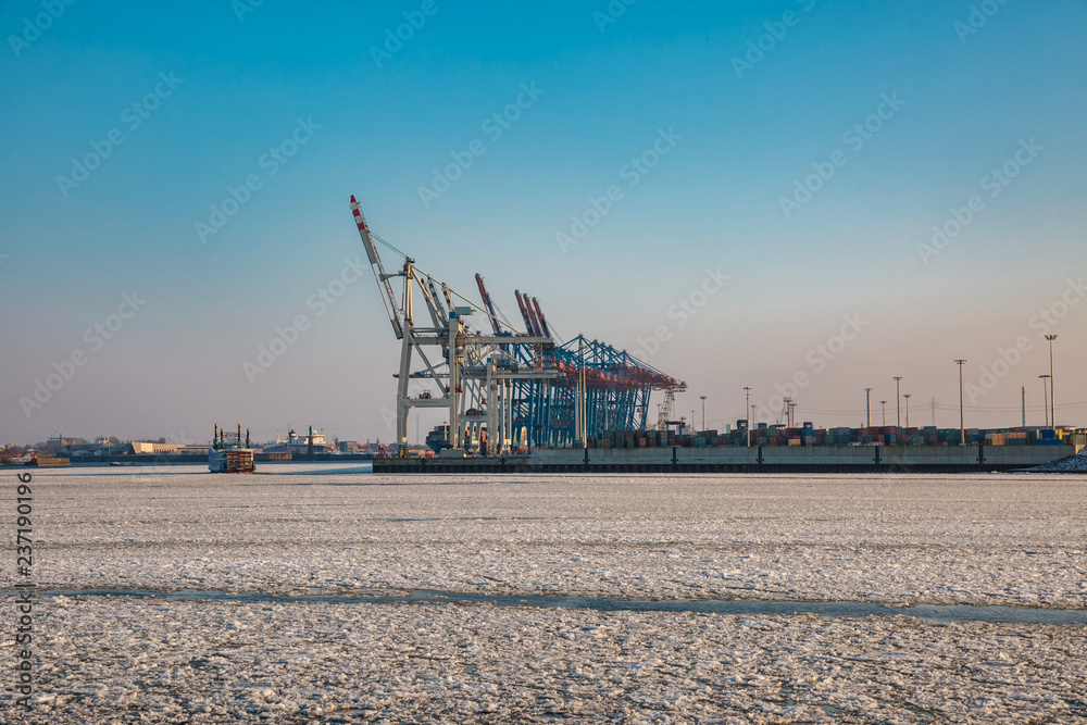 Blick auf die Hafenkräne im Hamburger Hafen bei Eis auf der Elbe