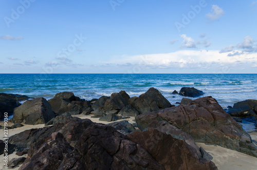Natural tropical beach, blue sky with rock & stone as foreground.