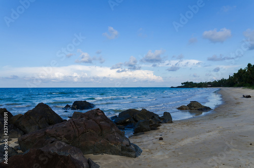 Natural tropical beach, blue sky with rock & stone as foreground.
