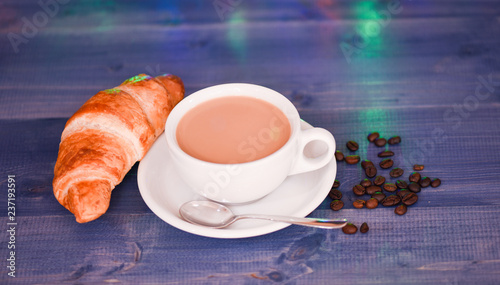 Fresh brewed coffee in white cup or mug croissant and beans on wooden blue background. Coffee drink winter holiday new year. Enjoying coffee on christmas morning. Coffee time christmas eve